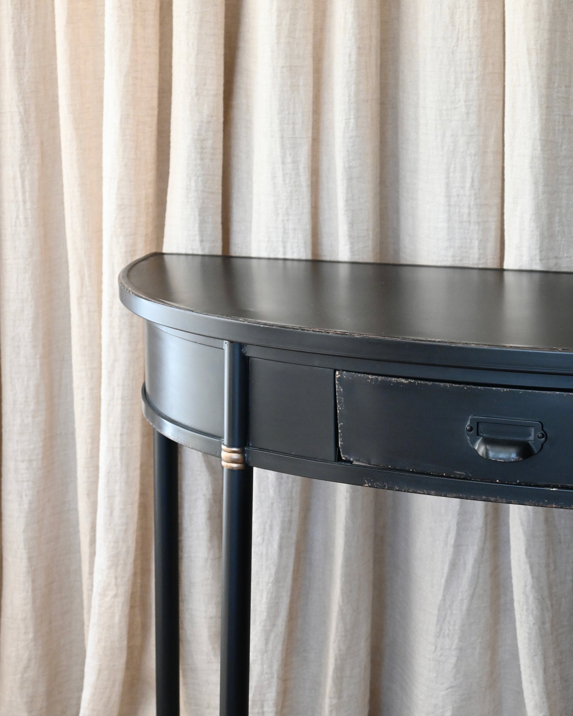 Consola semicircular en chapa negra con acabado envejecido.