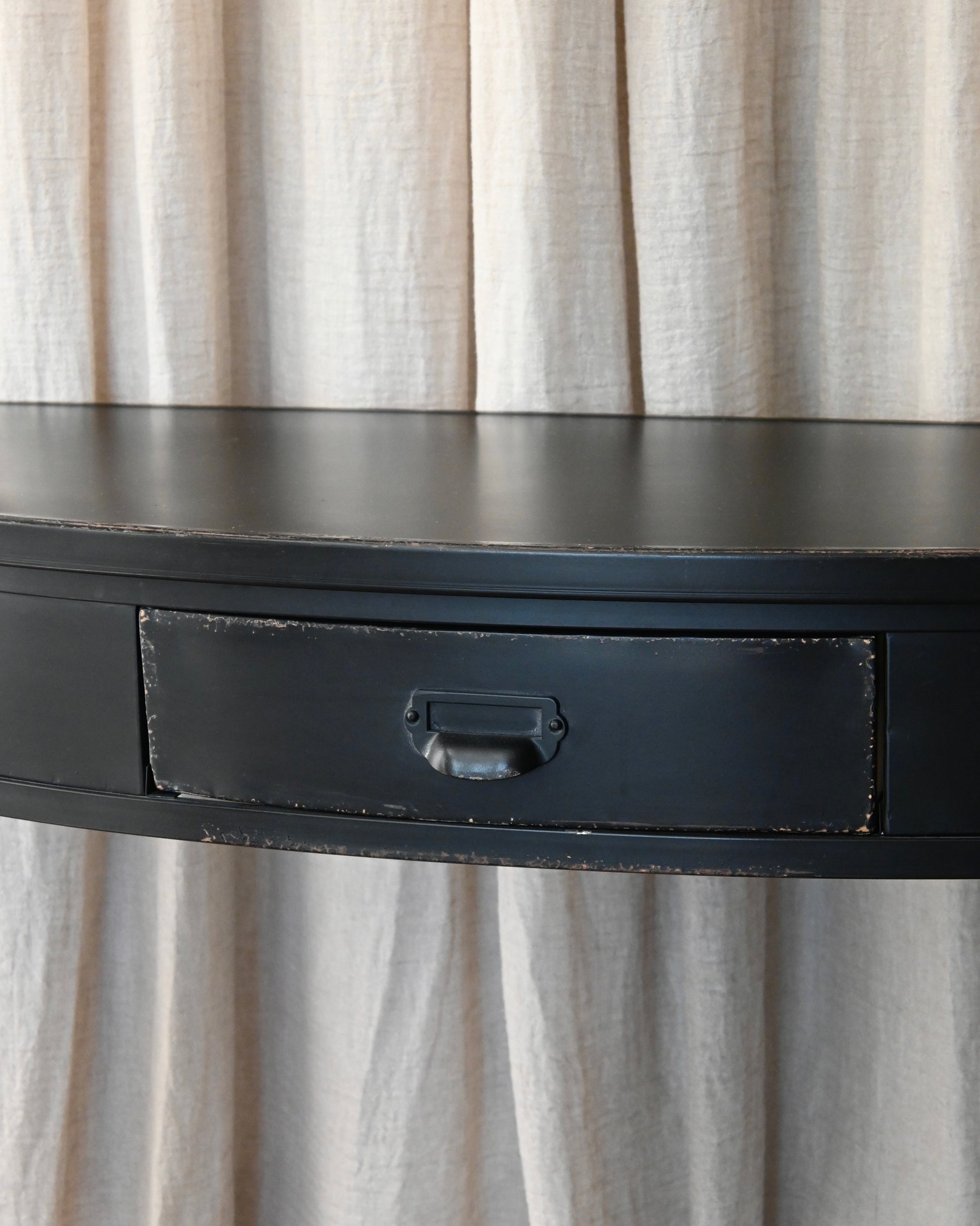 Consola semicircular en chapa negra con acabado envejecido.